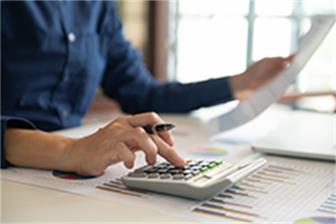 person using calculator with one hand and holding piece of paper with another 