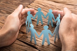 Hands around paper people standing in a circle.