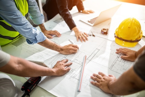 people reviewing building plans on a table 