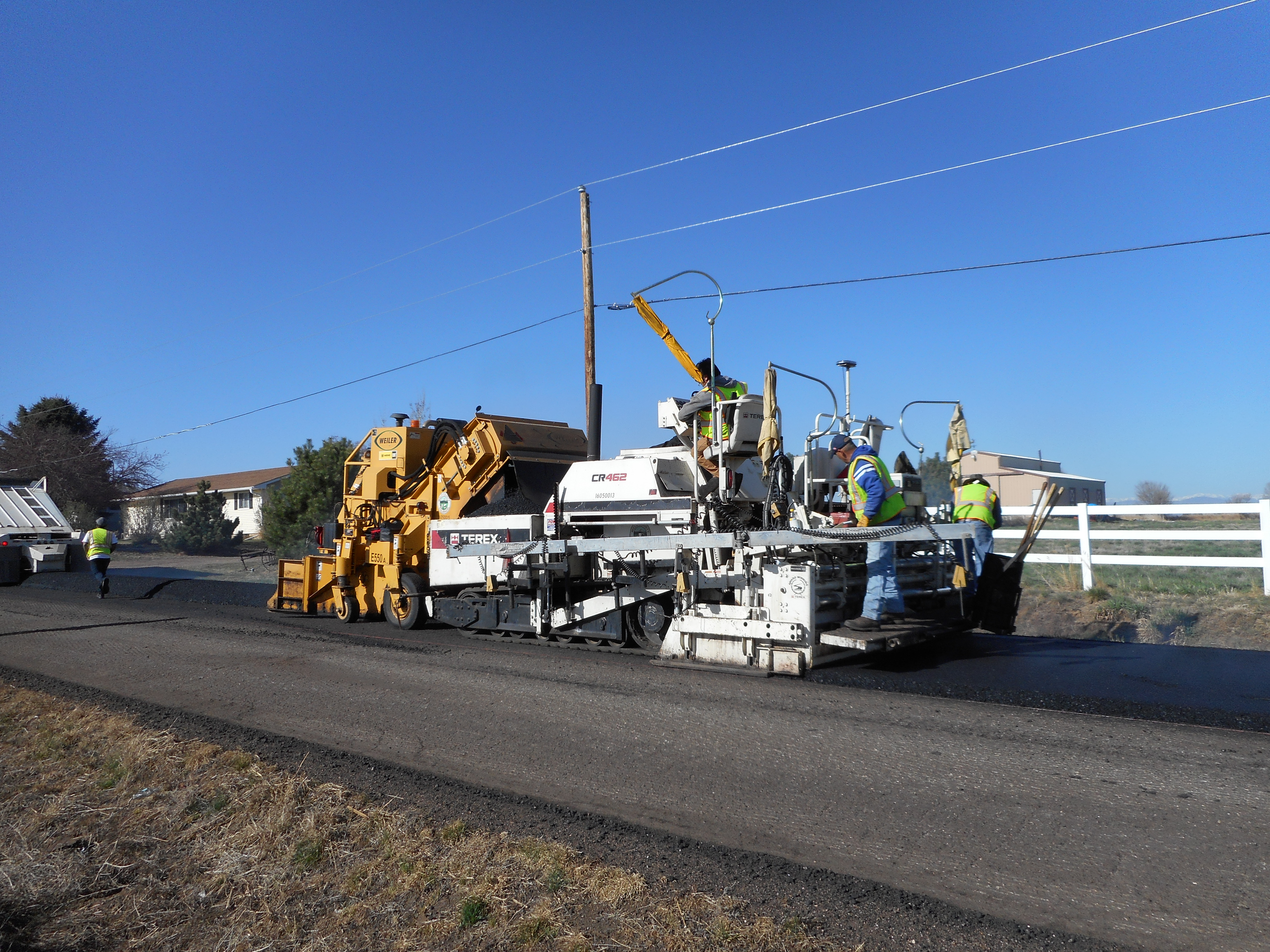Equipment placing asphalt on a stretch of road.