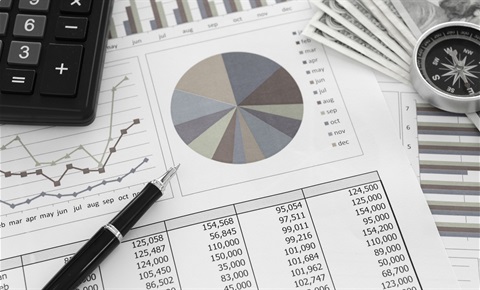 A calculator and pen sitting on a pie chart and other financial documents.