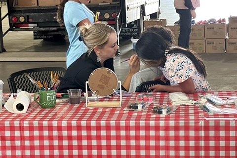 Woman painting a child's face at the Foster Appreciation Event on June 13.