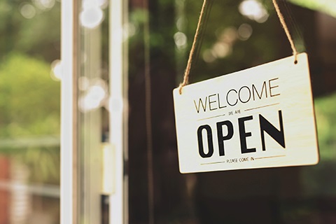 A sign hangs on a glass door that says, 
