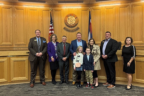 Brett Cavanagh, the newly appointed director of the Oil and Gas Energy Department, (center) standing with his wife, kids and the board of county commissioners.