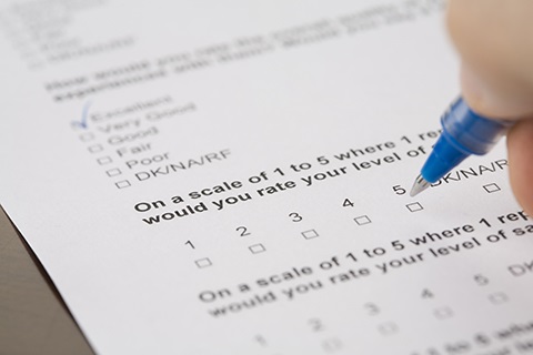 A person fills out a survey with a blue pen.