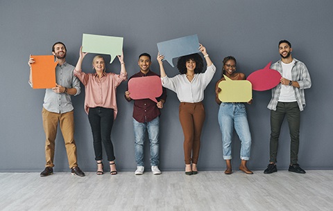 Six people dressed in business casual clothing hold up comment bubbles.