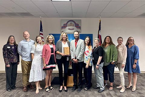 Commissioner Lynette Peppler stands with Department of Human Services staff while director Jamie Ulrich holds the C-Stat Distinguished Performance Award.