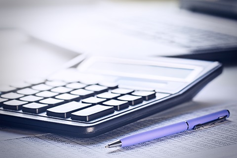 Pen and calculator on top of financial documents. 