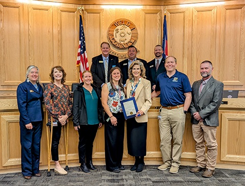 Staff from the Department of Health stand with the board of commissioners