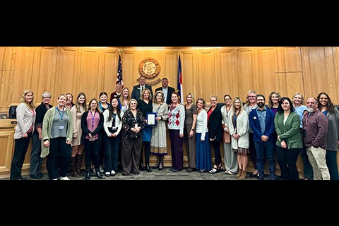 Department of Human Services Staff stand with the board of county commissioners in the hearing room.