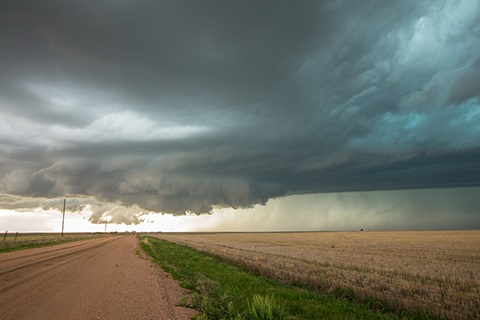 Storm clouds over a field and country road.
