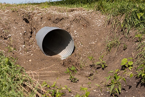 A culvert extending through dirt.