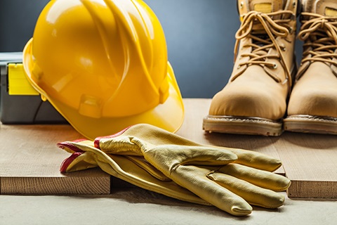 A hard hat sitting beside work boots and gloves.