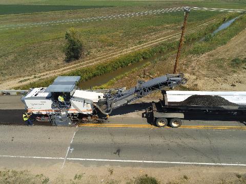 Equipment milling (removing) asphalt from a road before it is paved.